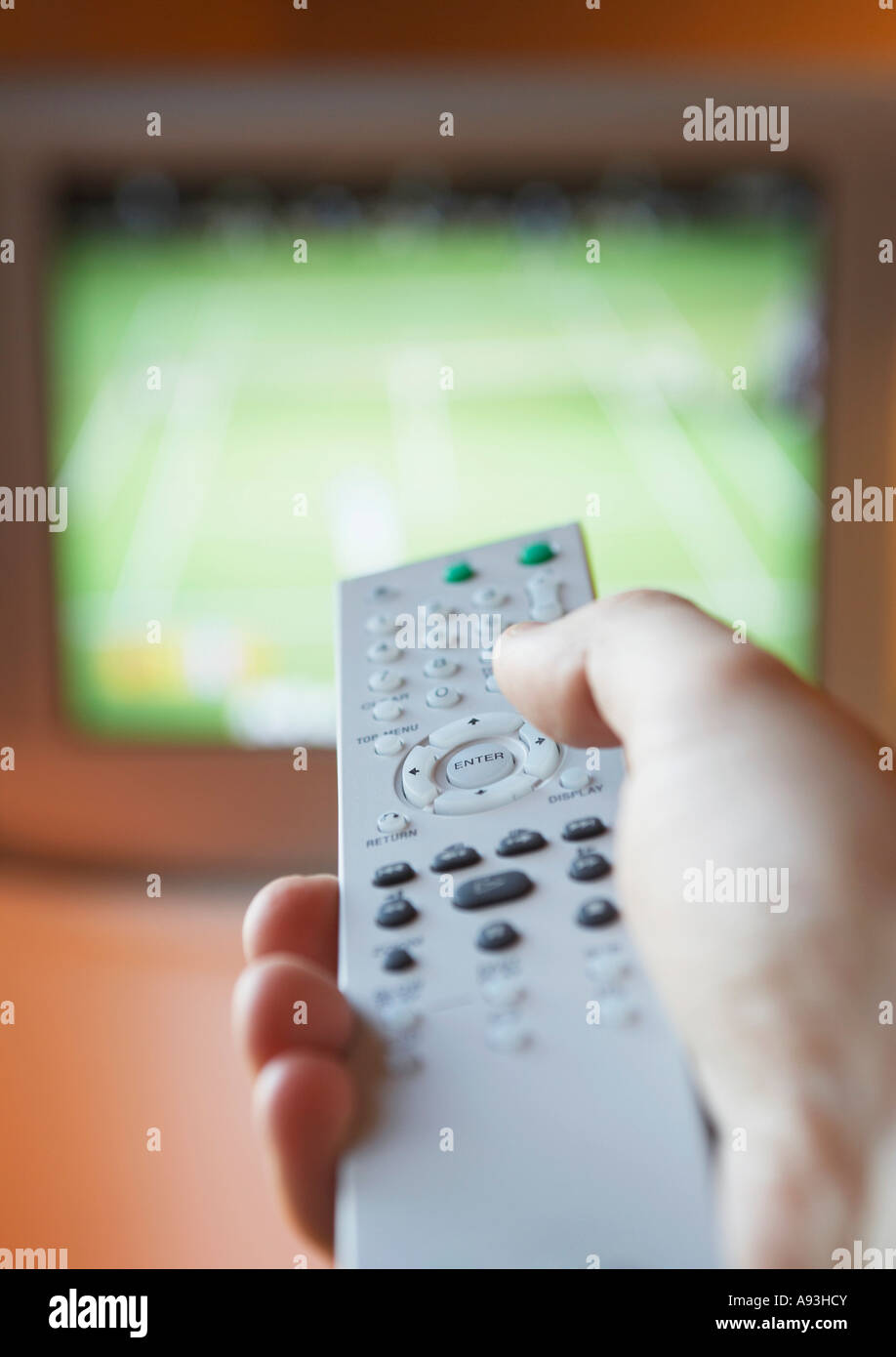 Man adjusting TV channel volume with remote control, closeup of hand