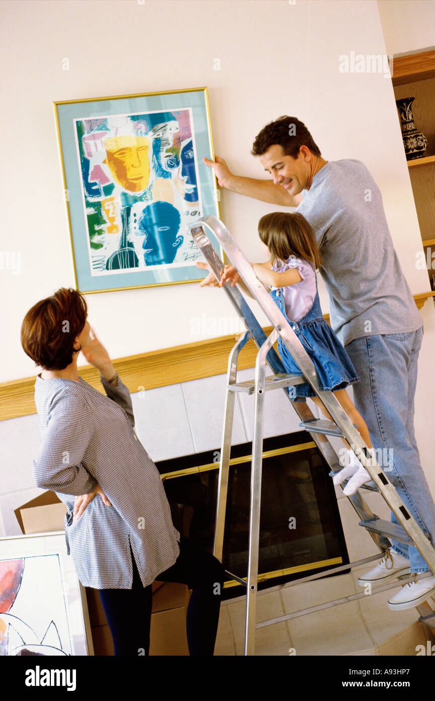Father and daughter hanging a painting on the wall Stock Photo