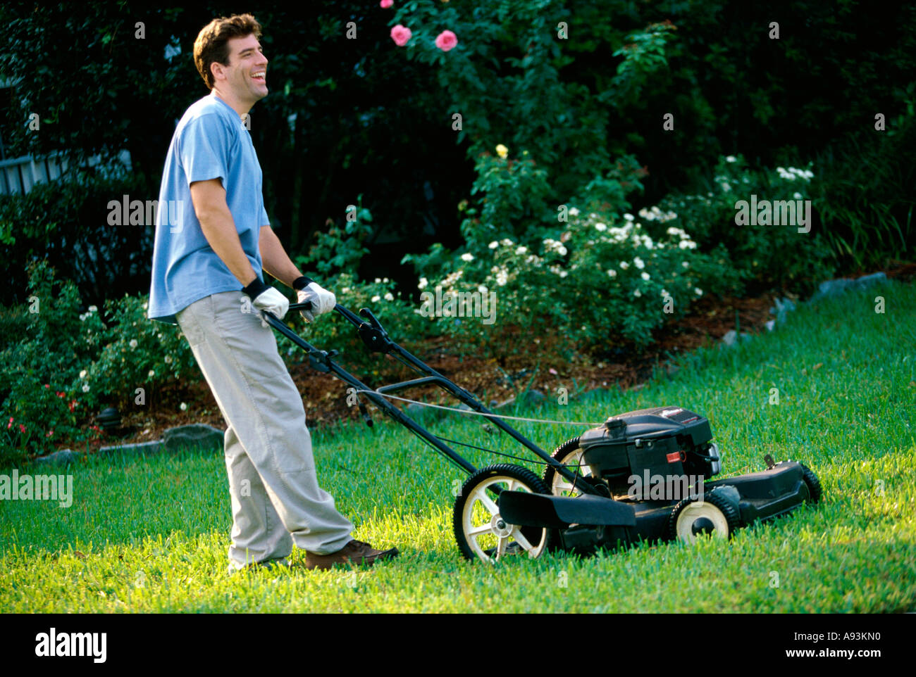 Side profile of a mid adult man mowing the lawn Stock Photo