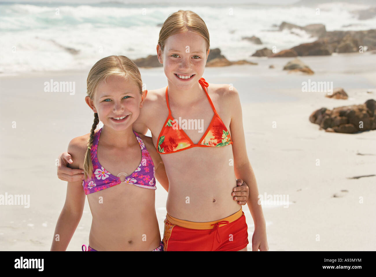 Two girls (7-9, 10-12) posing on beach, portrait Stock Photo - Alamy