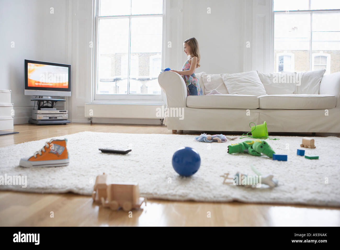 Girl (5-6) watching television, toys on floor in foreground Stock Photo