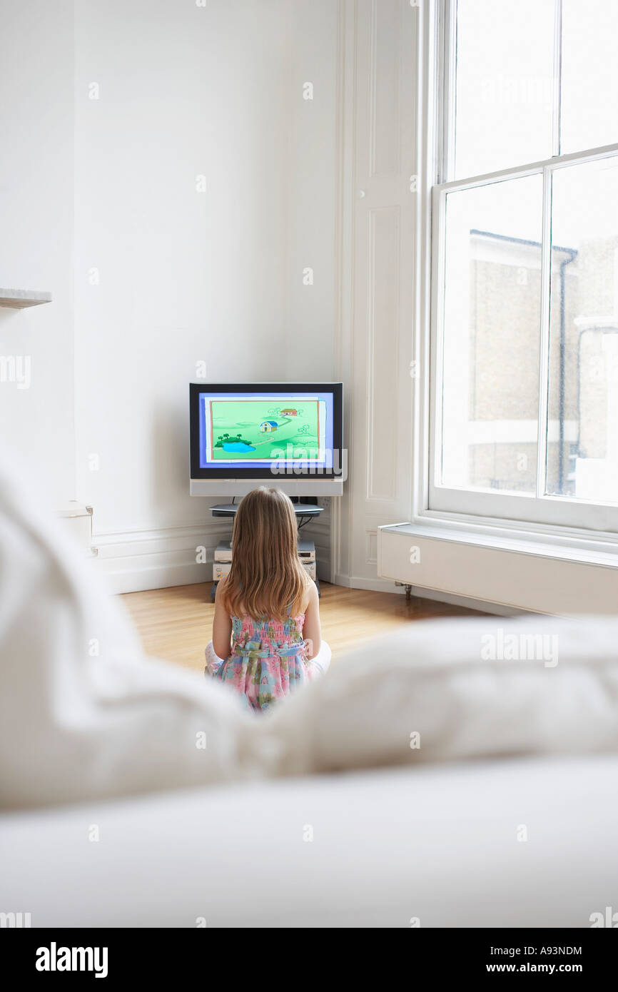 Girl (5-6) watching cartoons in television, back view Stock Photo