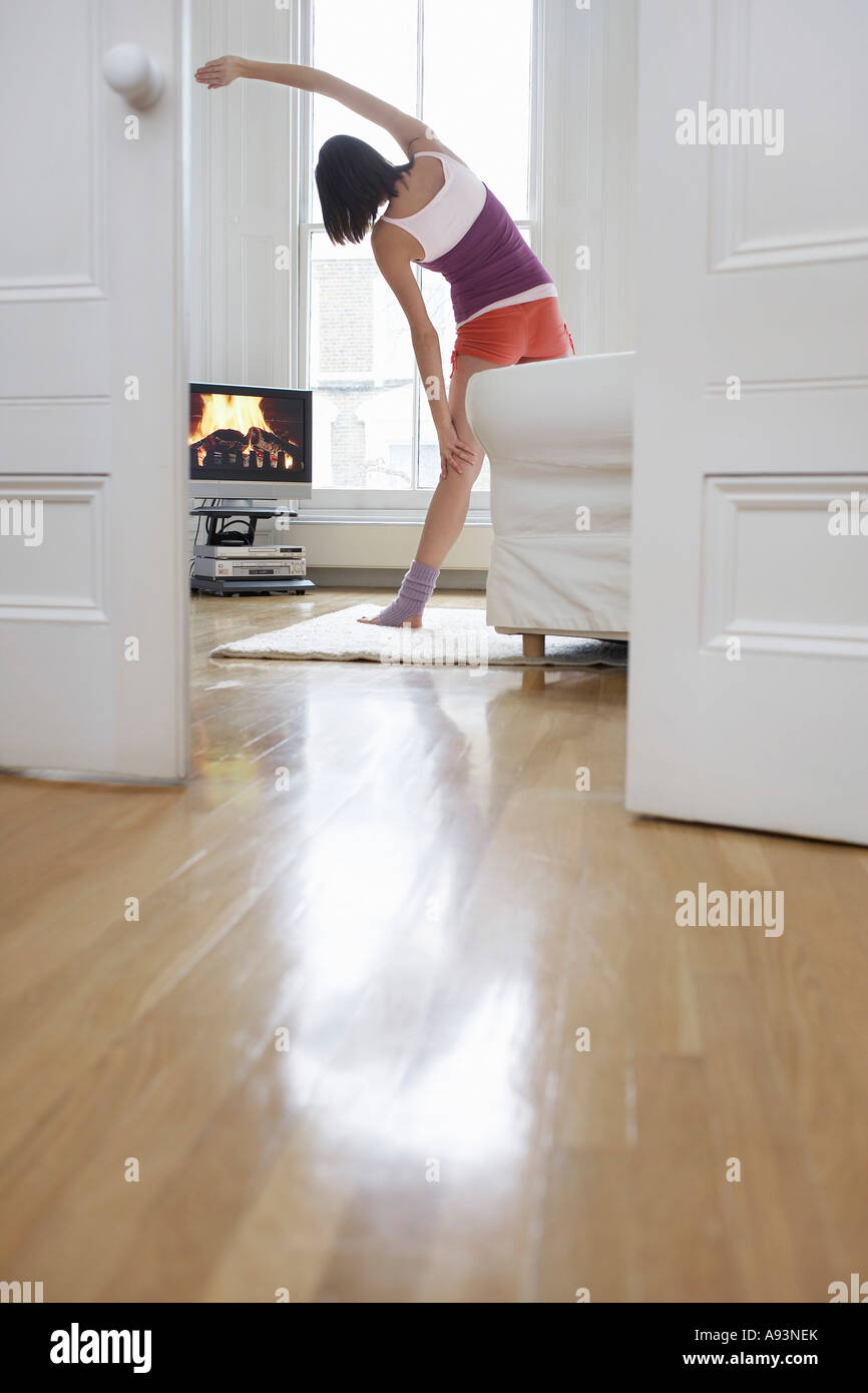 Woman exercising and watching television in living room, back view Stock Photo
