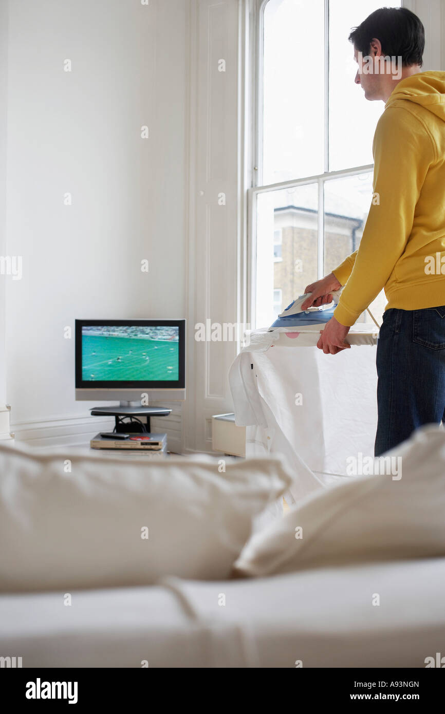 Man ironing and watching television Stock Photo