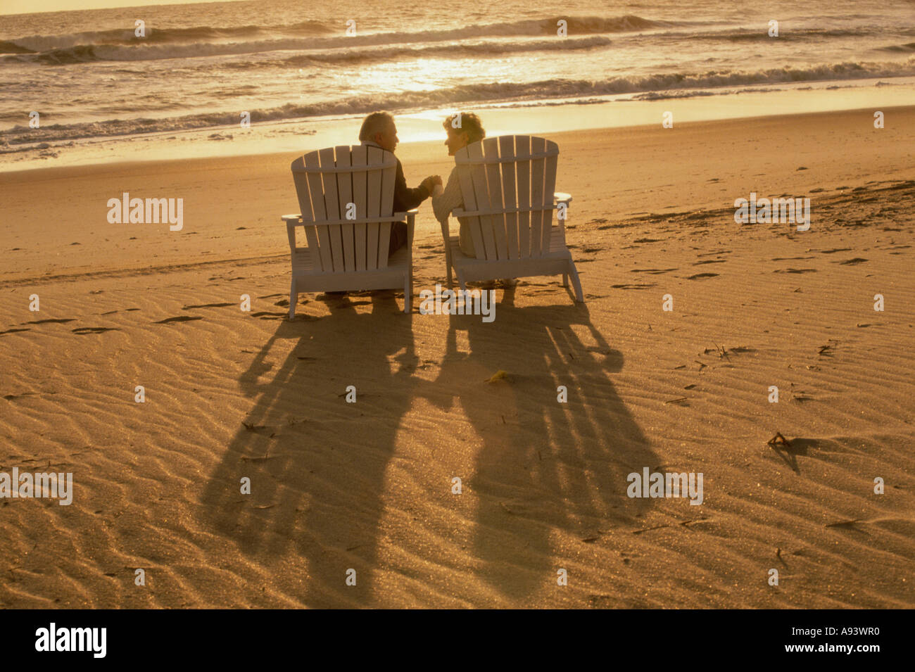 Rear view of a senior couple sitting together on the beach Stock Photo ...