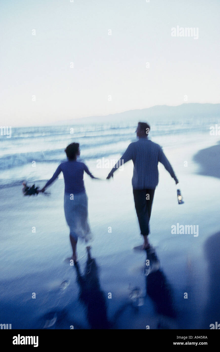 Rear view of a mid adult couple walking on the beach Stock Photo - Alamy