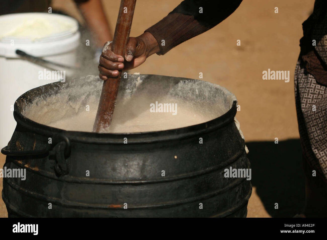 Motswana woman stirring traditional porridge in a three legged iron