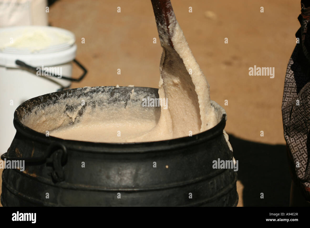 Motswana woman stirring traditional porridge in a three legged iron