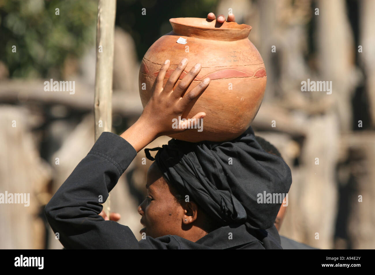 Woman wearing black shawl carrying clay pot on her head Gaborone Botswana Stock Photo