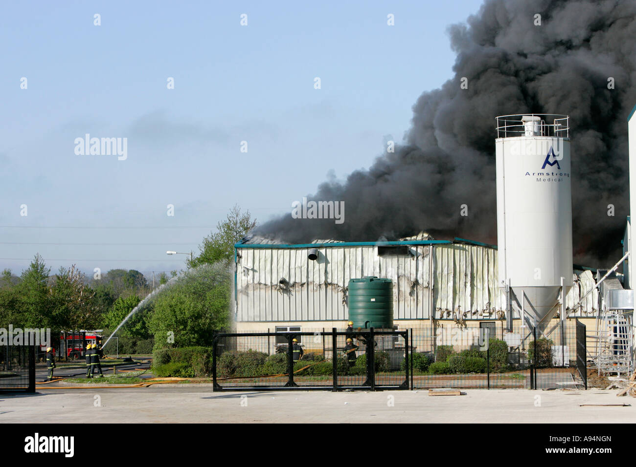firefighters fighting a large industrial fire with water and hoses at