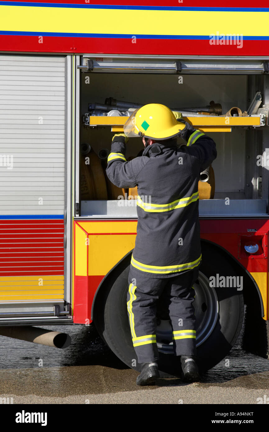 firefighter in protective clothing reaches into fire engine for equipment during incident Stock Photo