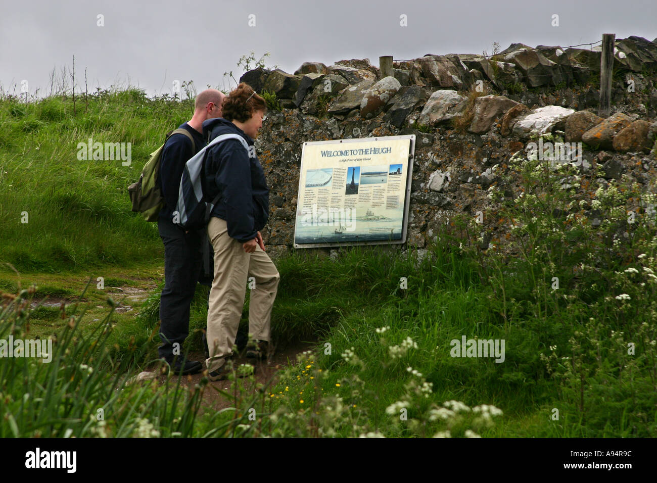 Walkers studying a mounted map and data board on Holy Island Lindisfarne Stock Photo