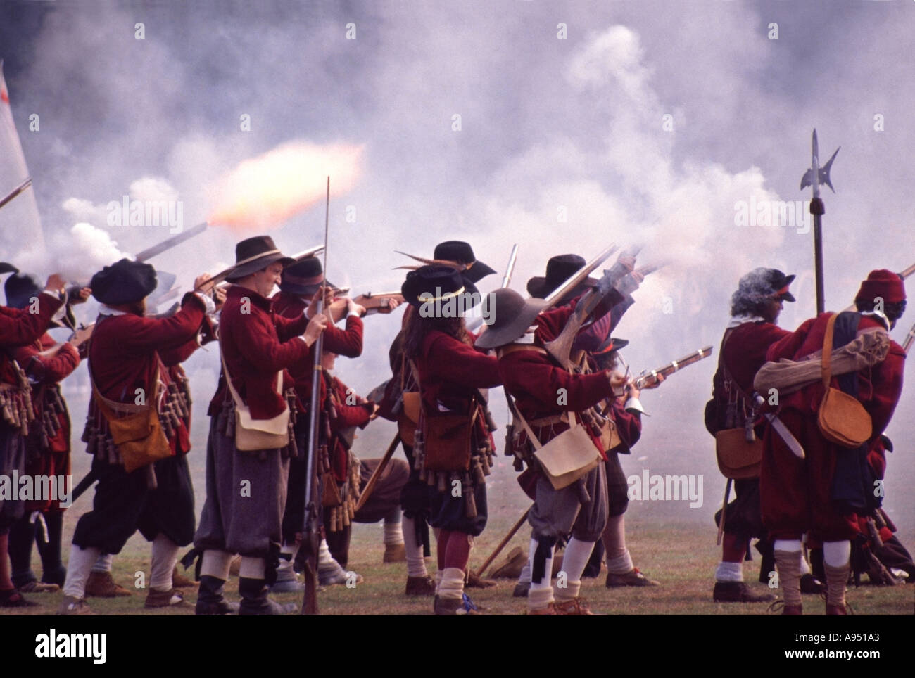 English Civil War reenactment by groups like English Civil War Society & Sealed Knot soldiers firing musket gun in battle flame & smoke period costume Stock Photo