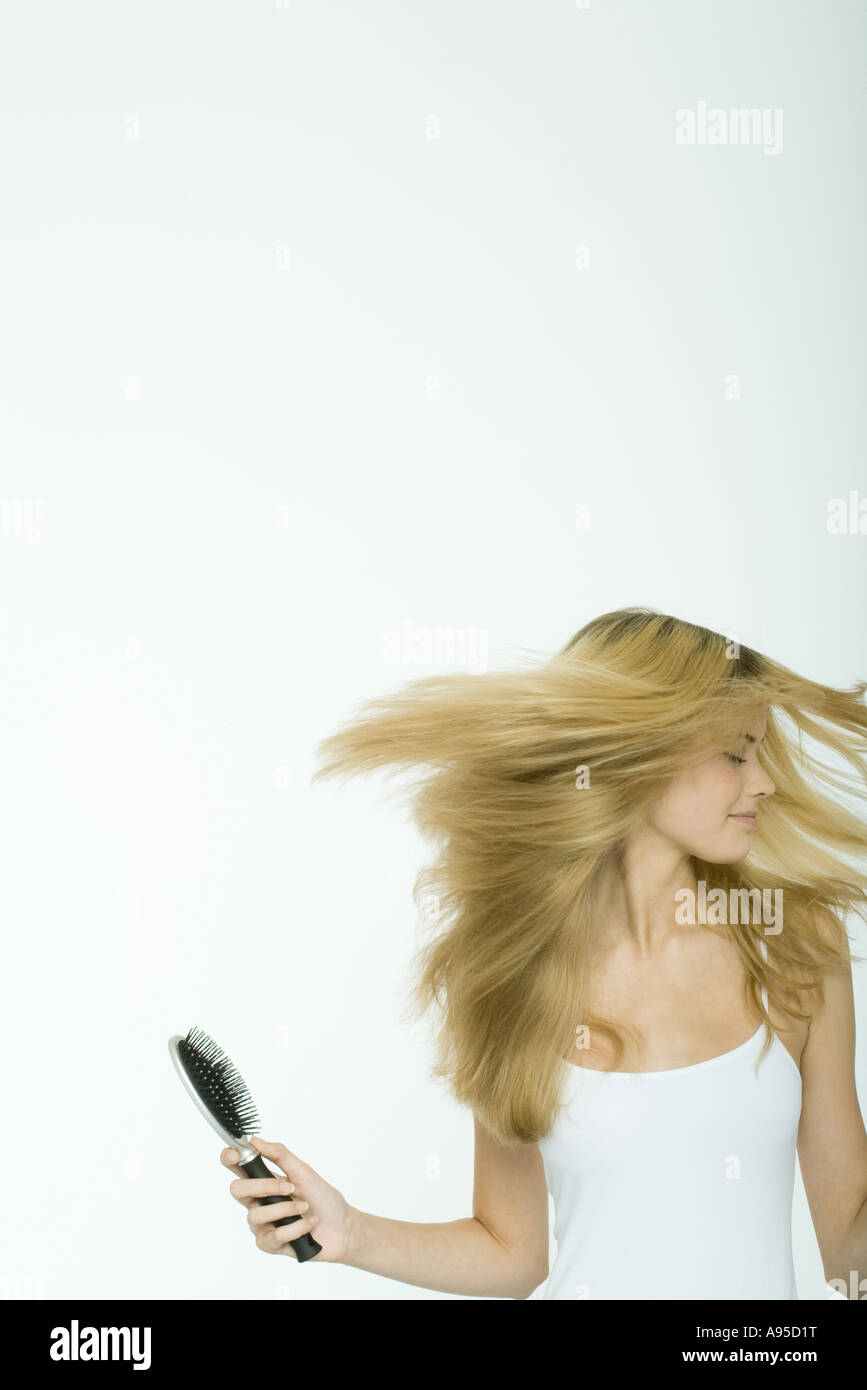 Teenage girl holding brush and swinging hair Stock Photo