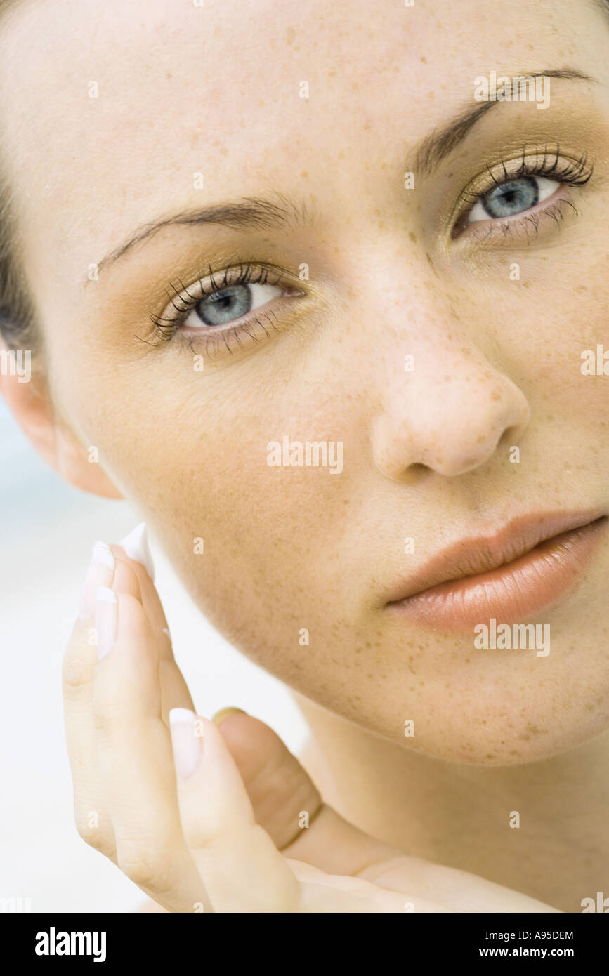 Woman applying sunscreen to face, close-up Stock Photo
