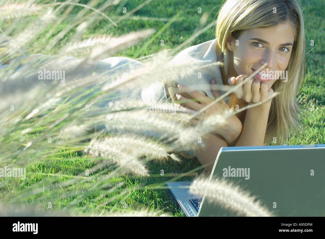 Young woman lying in field with laptop Stock Photo