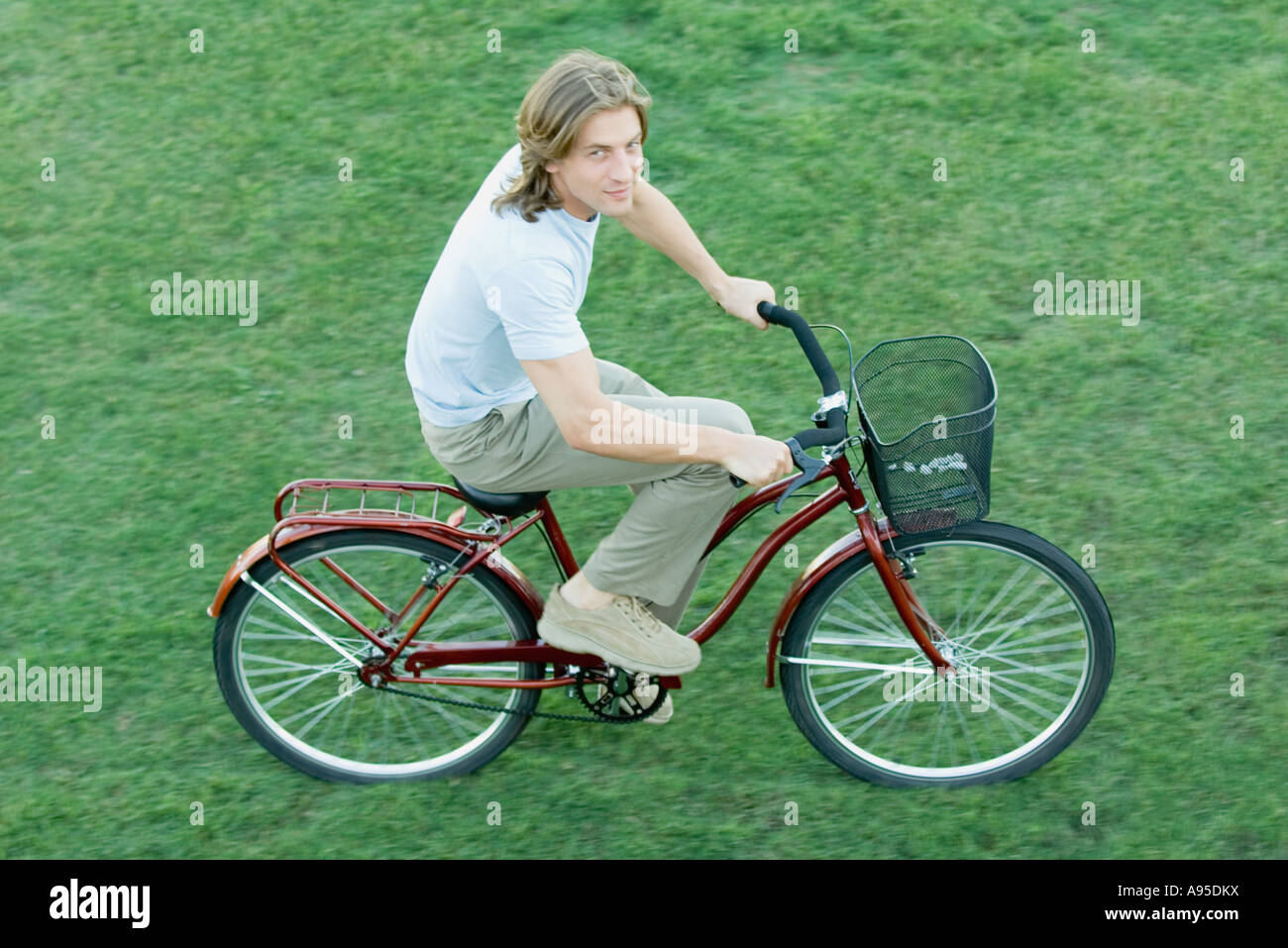 Young man riding bicycle on grass, high angle view Stock Photo