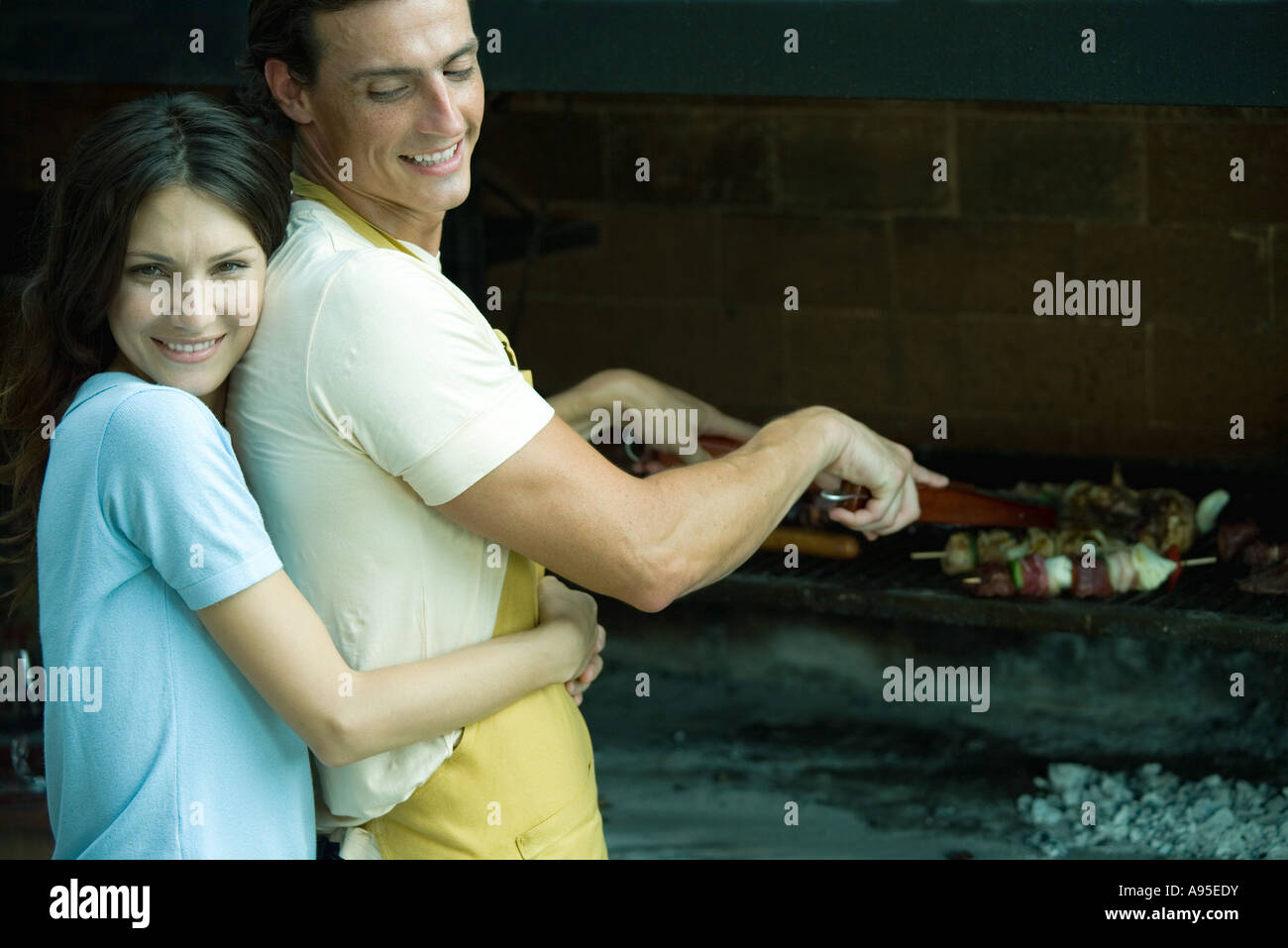 Couple having cookout, woman hugging man from behind Stock Photo - Alamy