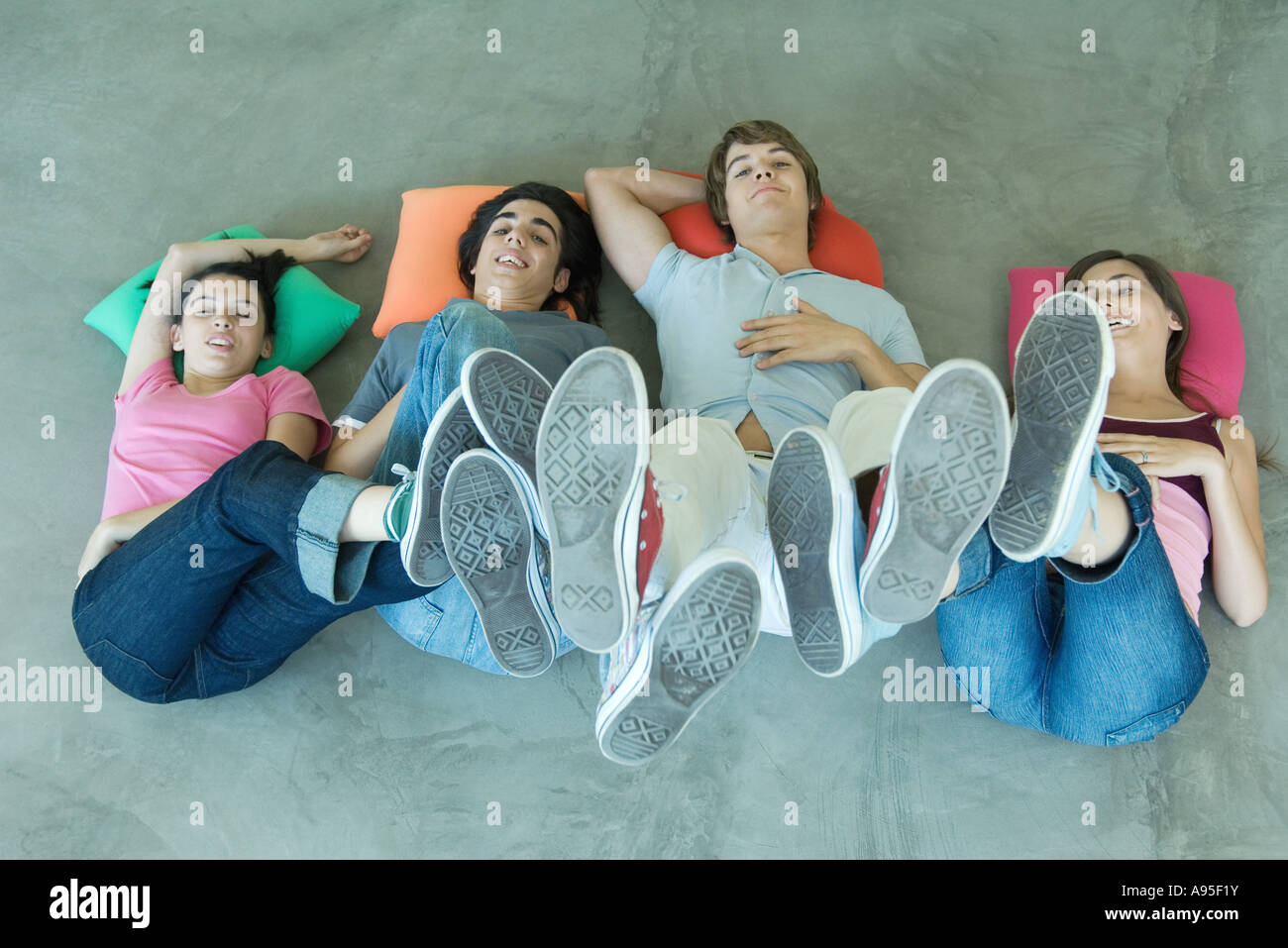 Teenage friends lying on floor with feet in the air, view from directly above Stock Photo