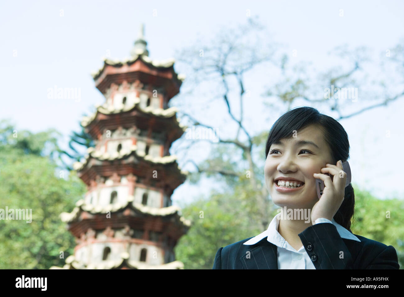 Young woman using cell phone, pagoda in background Stock Photo