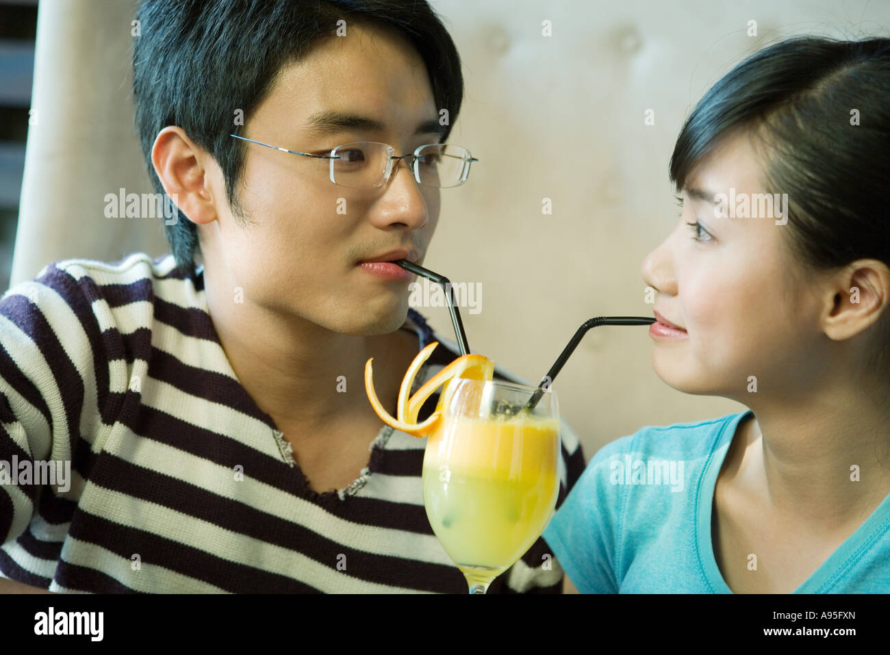Young couple sharing cocktail with two straws Stock Photo Alamy