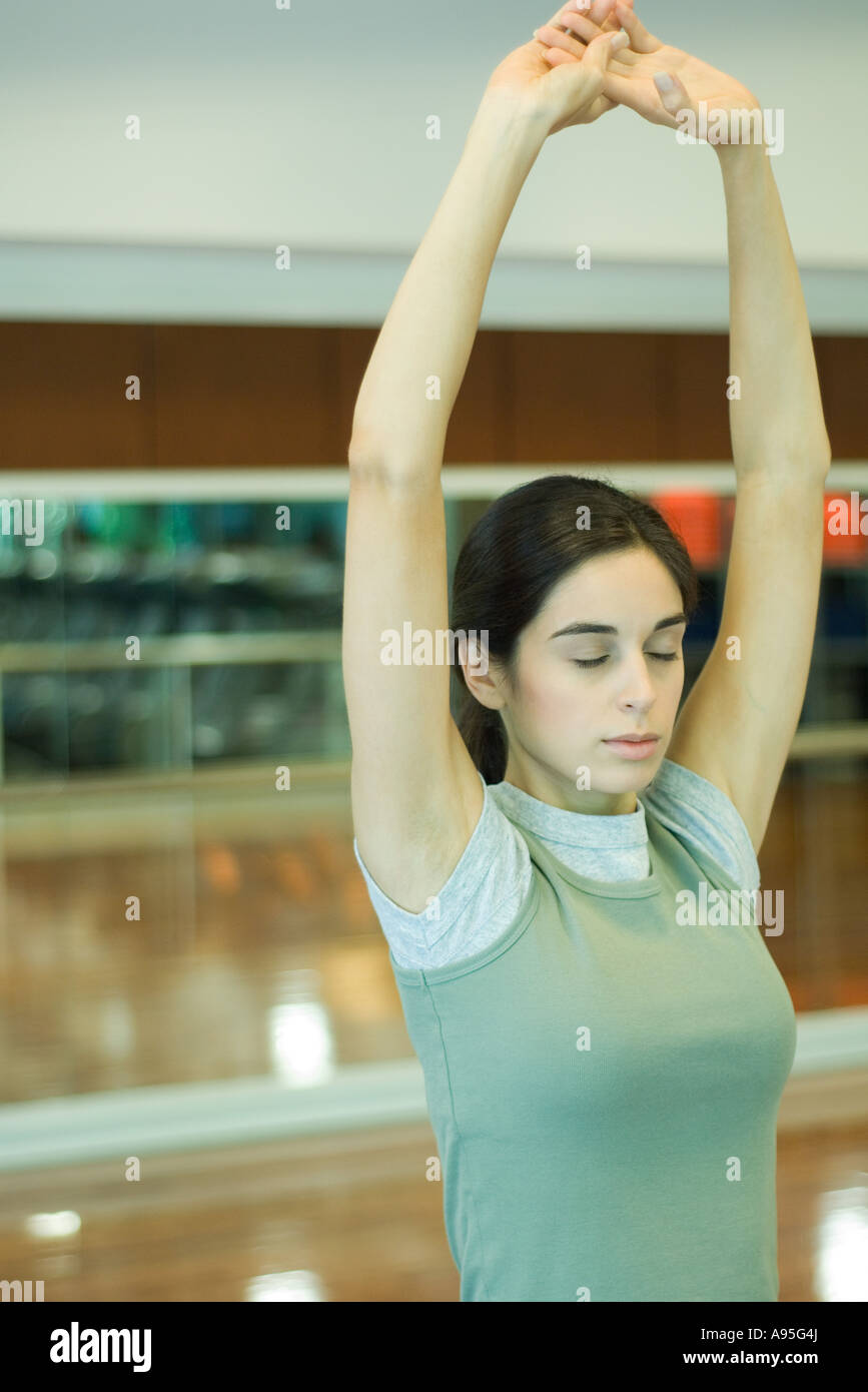 Young woman stretching arms overhead, eyes closed Stock Photo - Alamy