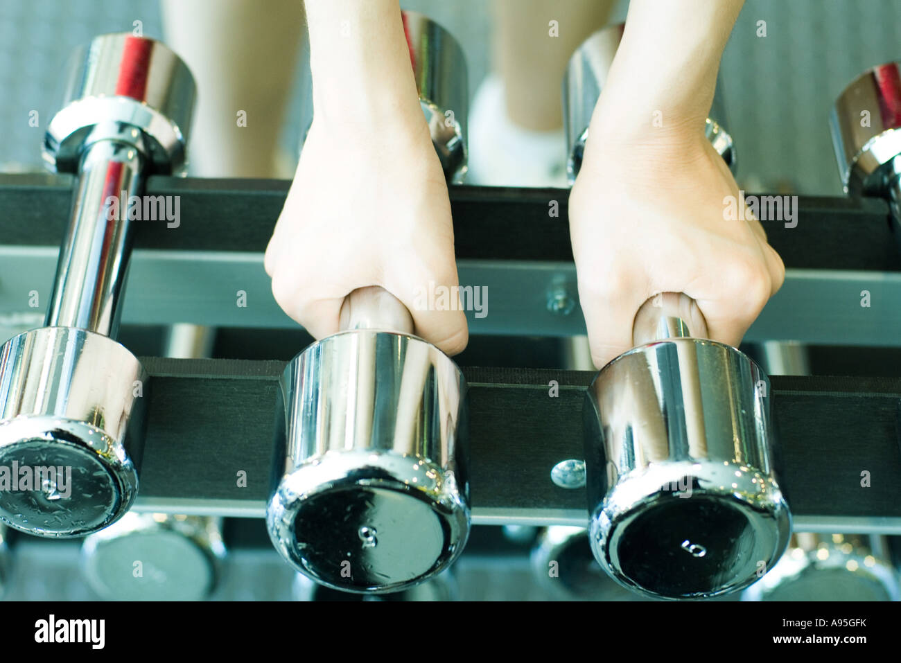 Woman picking up dumbbells Stock Photo