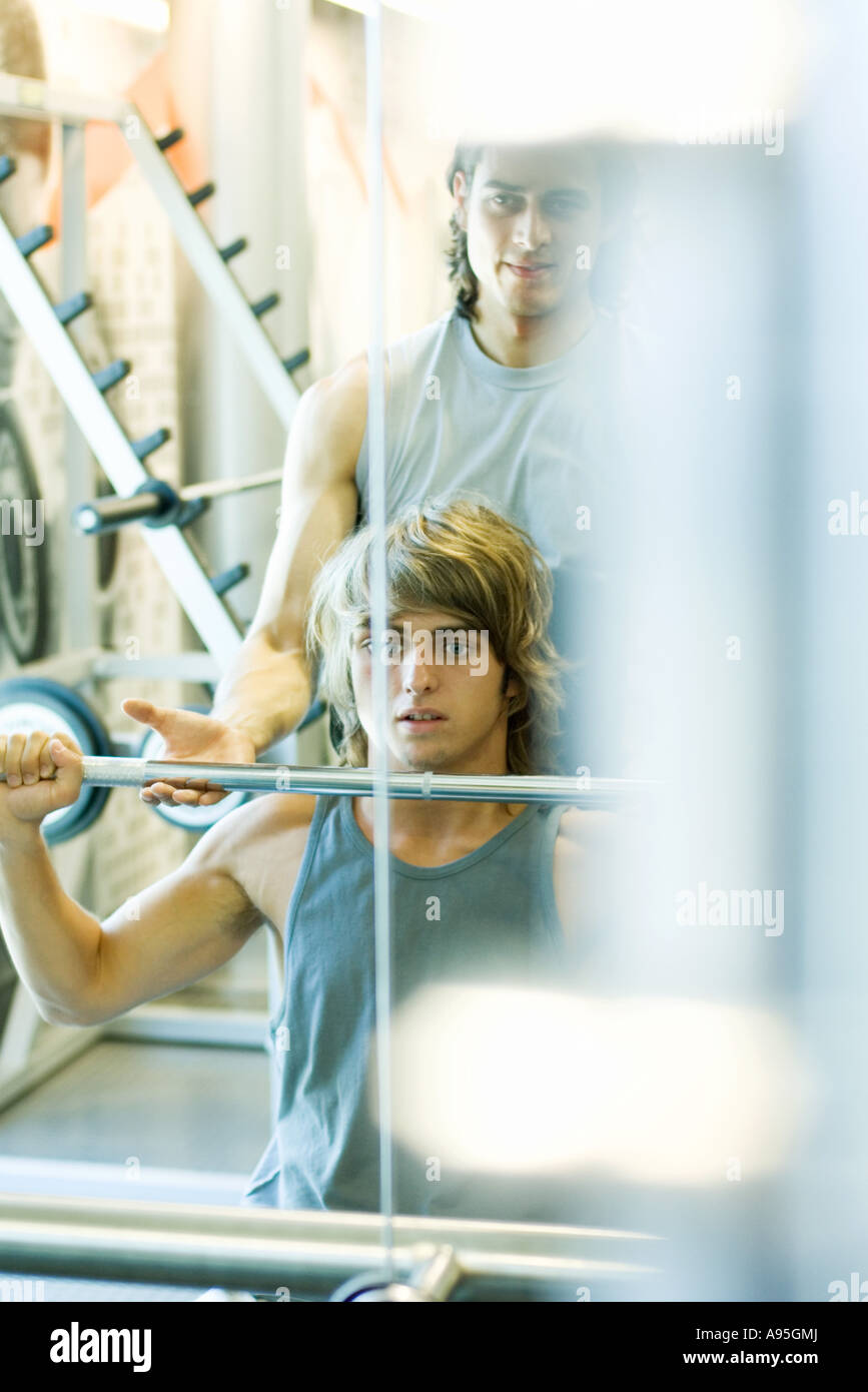 Man lifting barbell while second man spots Stock Photo