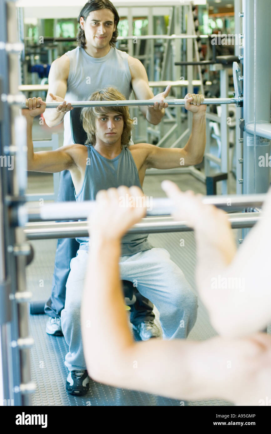 Man lifting barbell while second man spots Stock Photo