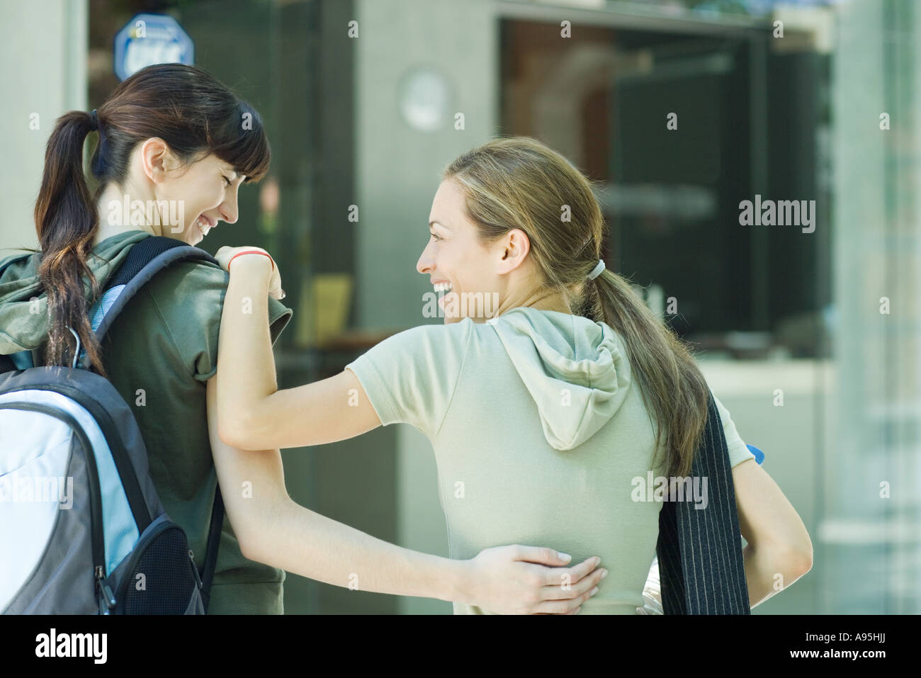 Two young women with arms around each other, laughing, rear view Stock ...