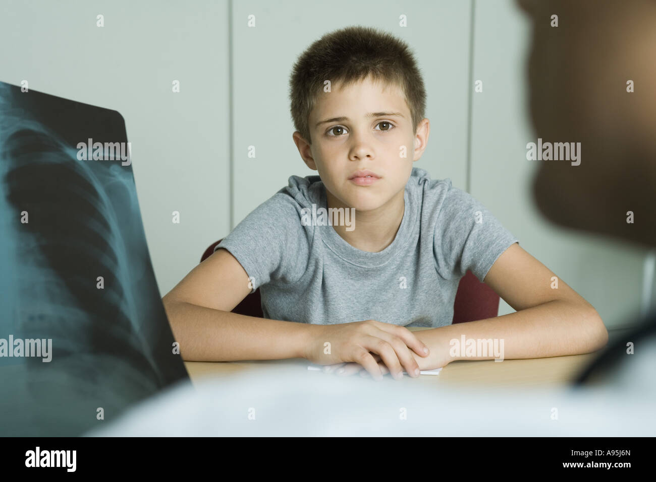 Doctor sitting across from boy, looking at x-ray Stock Photo