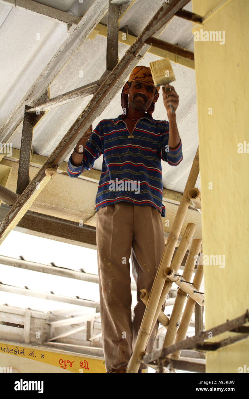 Workman painting roof girders at Bhuj Bus Stand, Gujarat, India Stock