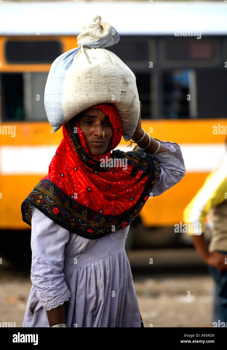 Tribal Indian woman from Kutch district carrying sack on head at bus-stand, Bhuj, Gujarat, India Stock Photo