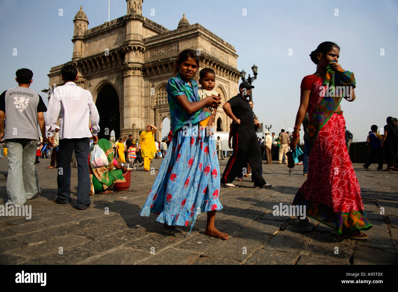 Young Indian hawker holding younger brother in arms at Gateway of India
