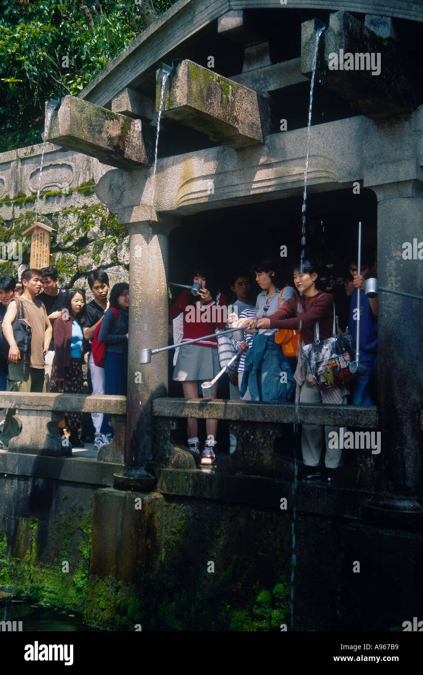 People queuing to catch water in cups using poles as drinking the water