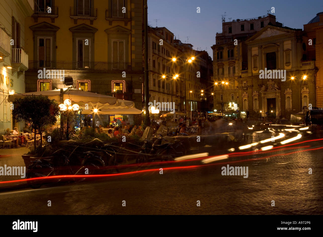 A nightscene in an Italian street shot with a long exposure to show the movement of traffic around the restaurant Stock Photo