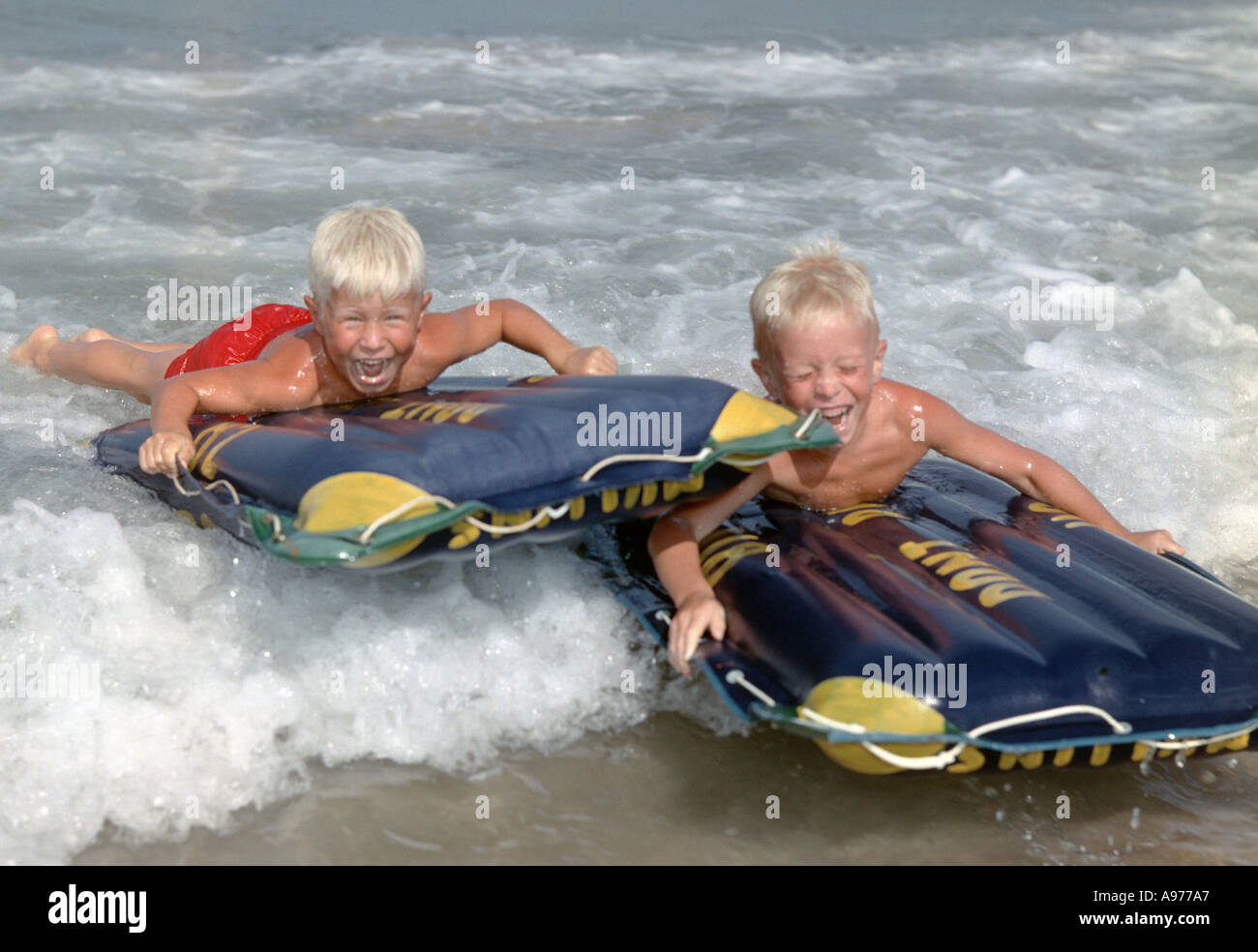 two boys on rubber rafts riding the waves in ocean surf Stock Photo - Alamy