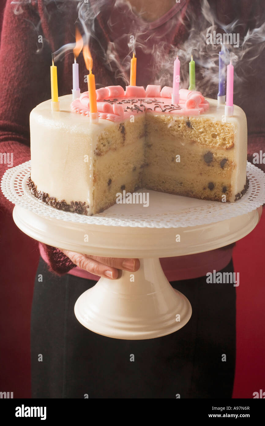 Woman serving birthday cake with blown out candles FoodCollection Stock