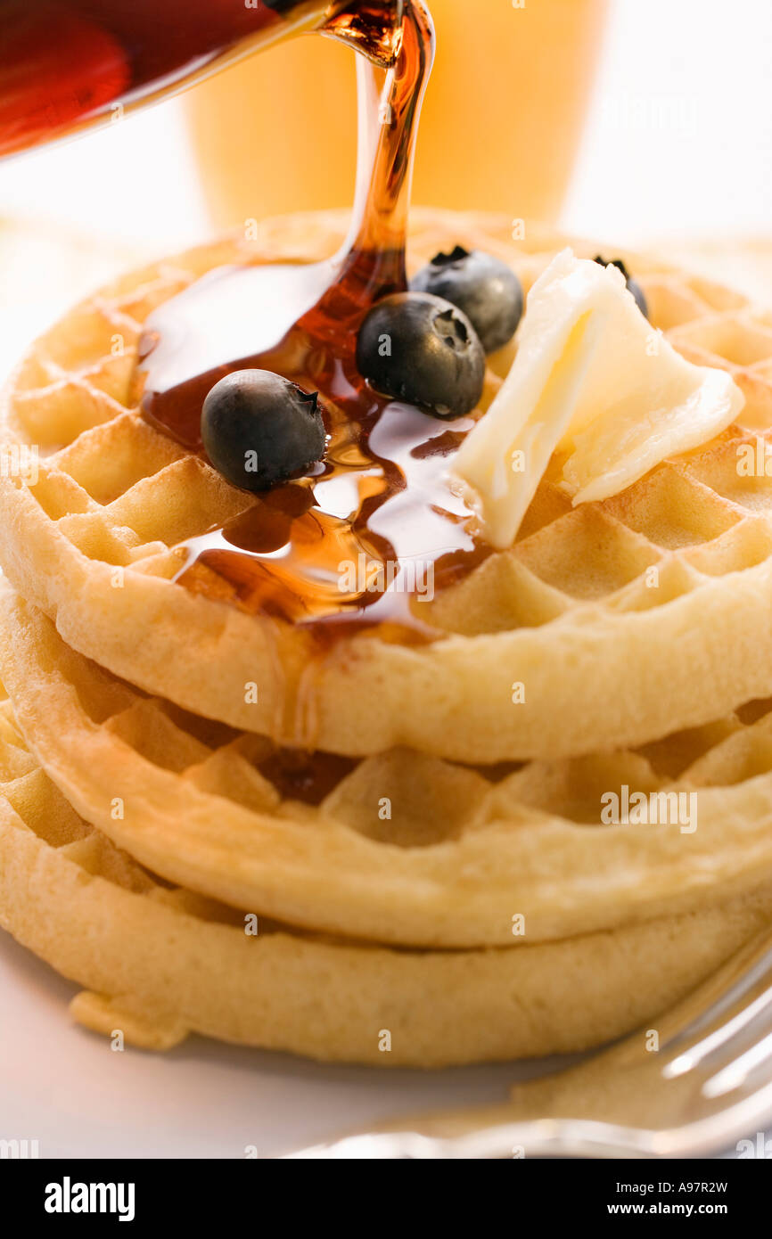 Pouring maple syrup over waffles with butter berries 1 FoodCollection