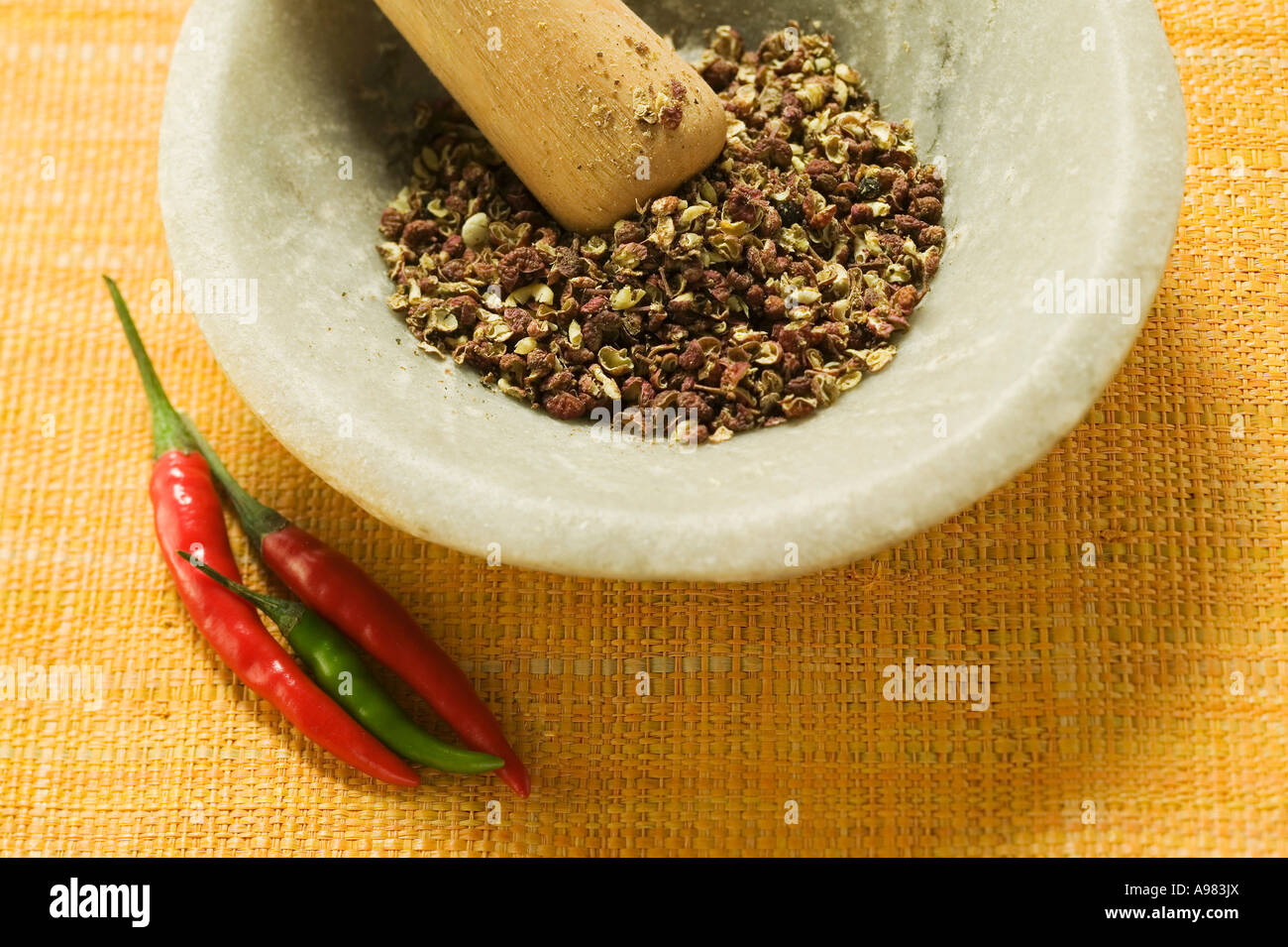 Szechuan pepper in mortar chili peppers beside it FoodCollection Stock Photo