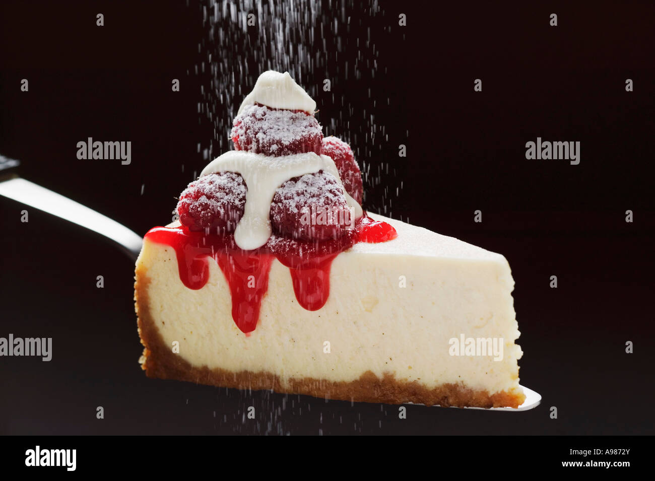 Slice of cheesecake with raspberries cream icing sugar on server ...