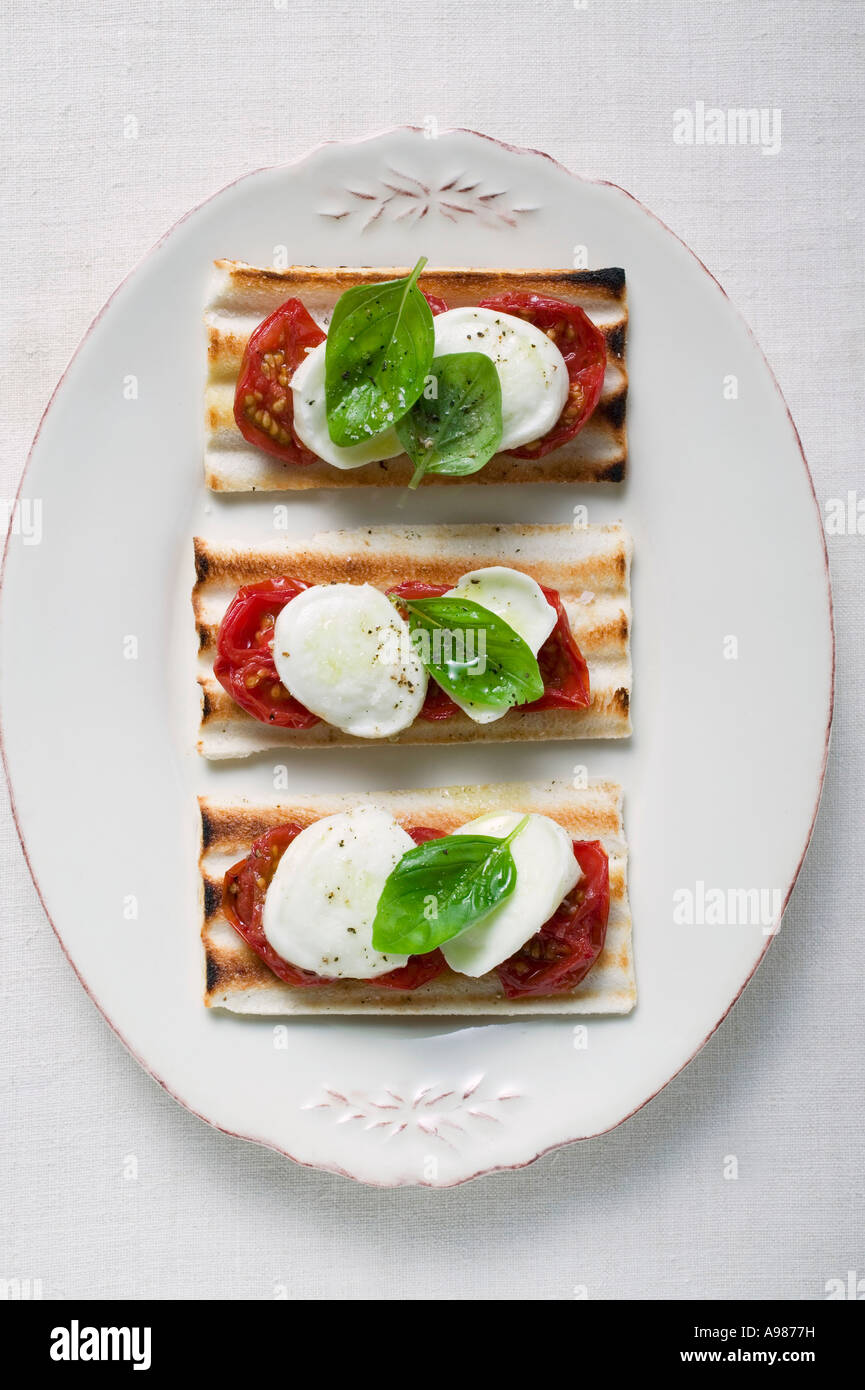 Three tomato and mozzarella toasts with basil FoodCollection Stock