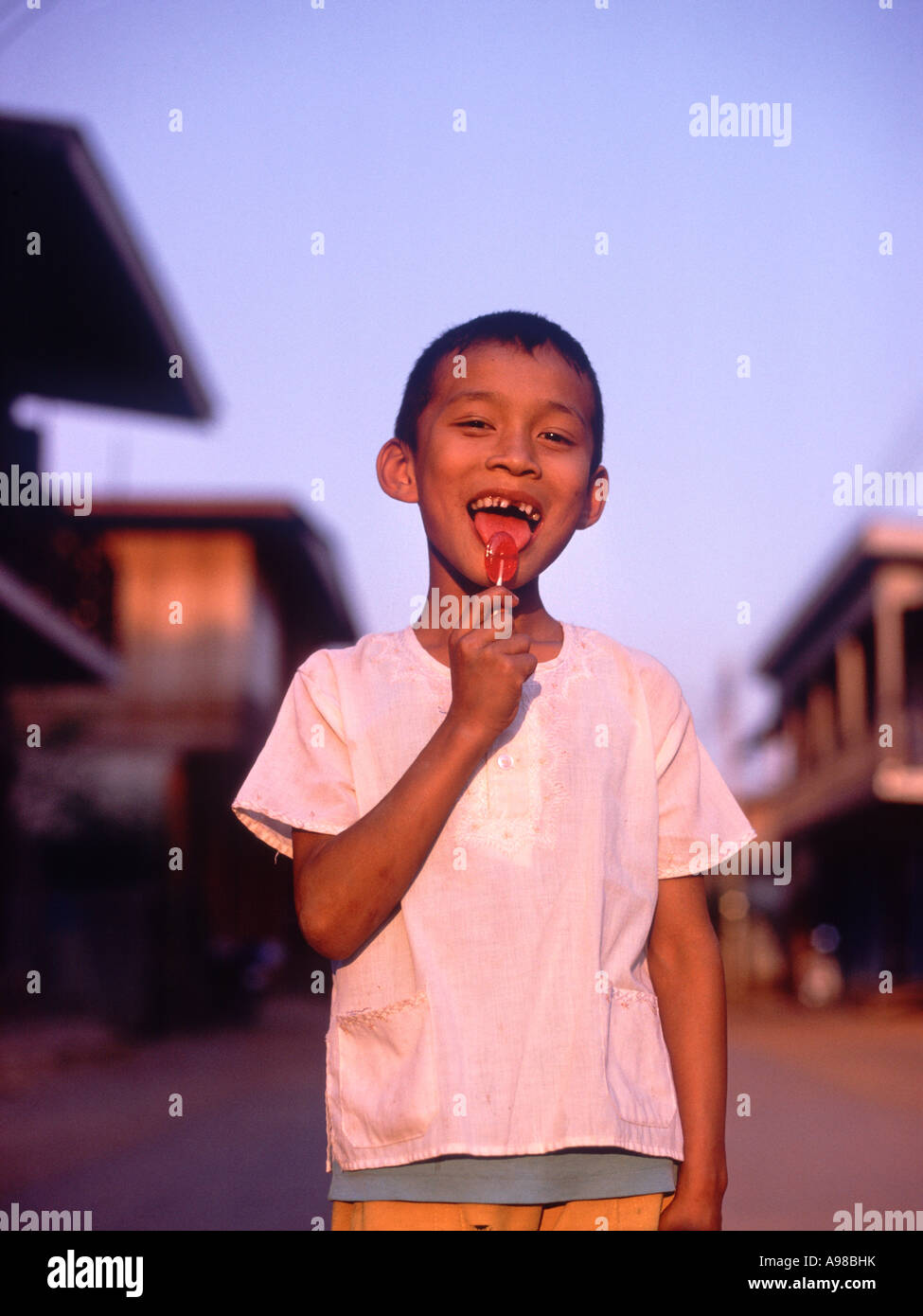 Smiling boy licking candy sucker in street, Chiang Khaen, NE Thailand, Asia Stock Photo