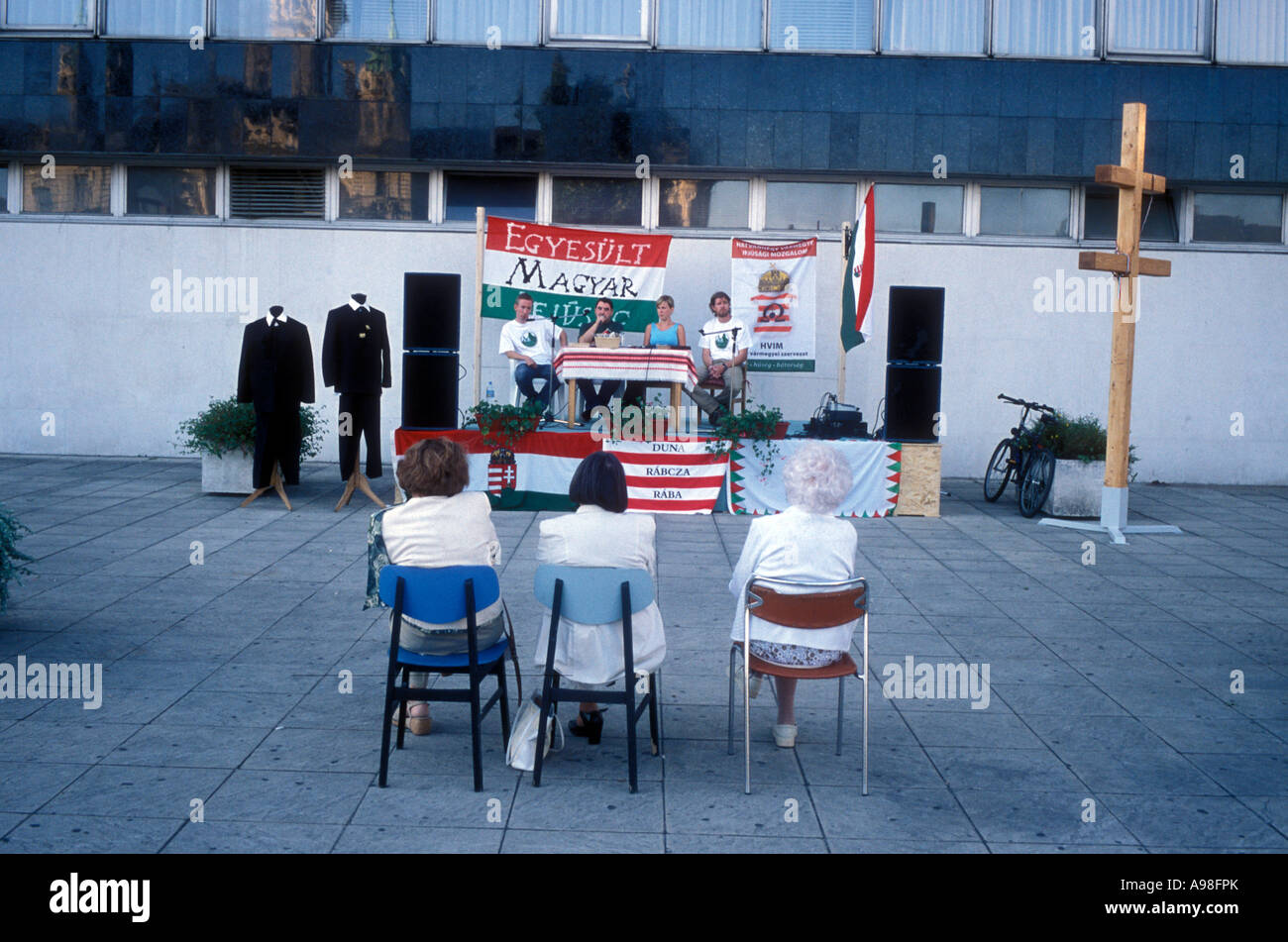 Three Women Sit On Folding Chairs And Watch Four People On