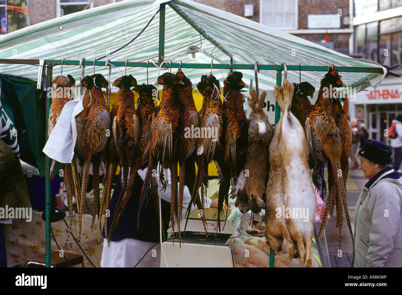 Pheasants, hares and rabbits hanging on a market stall in York Farmer's Market Stock Photo