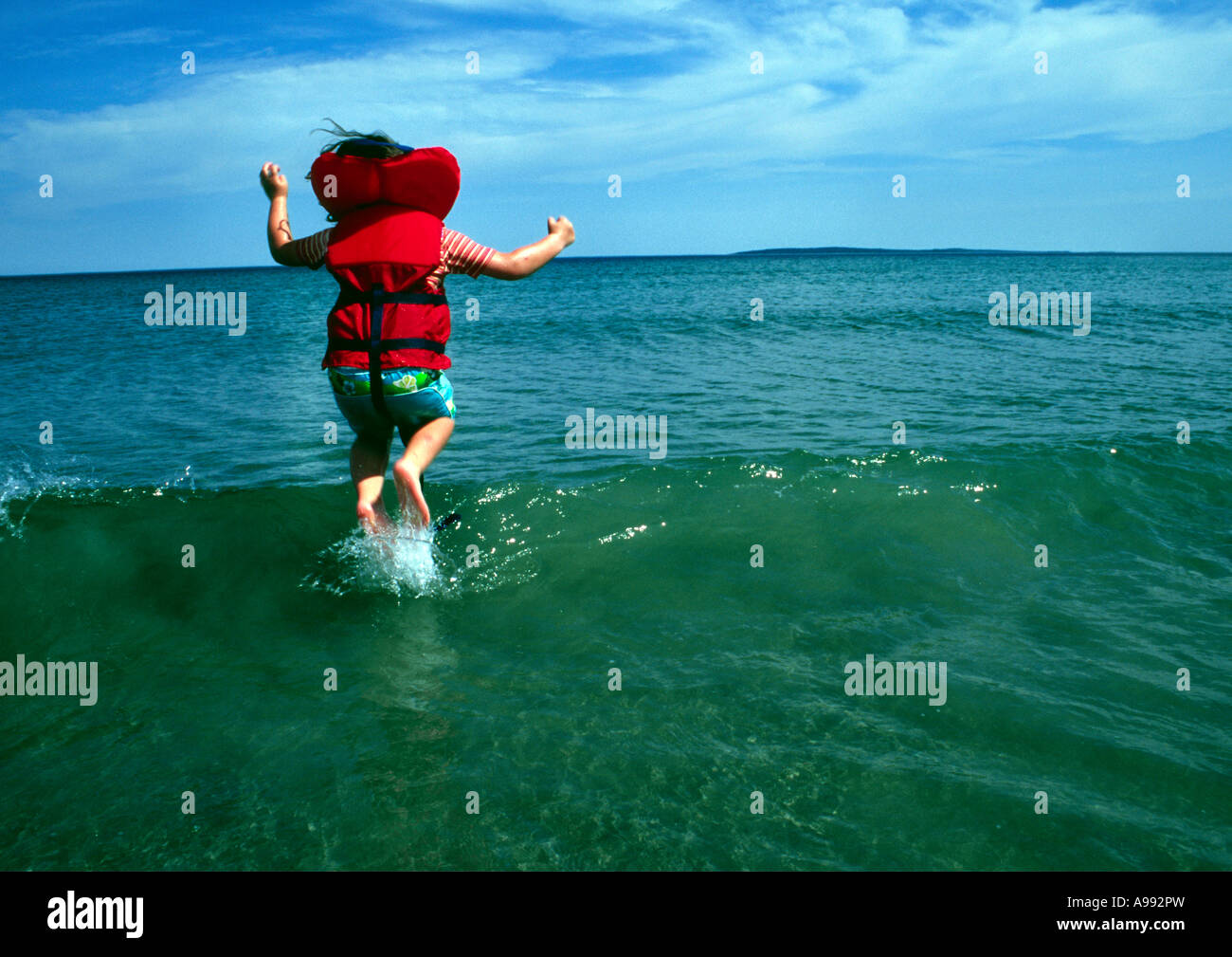 child jumping waves at the beach Stock Photo