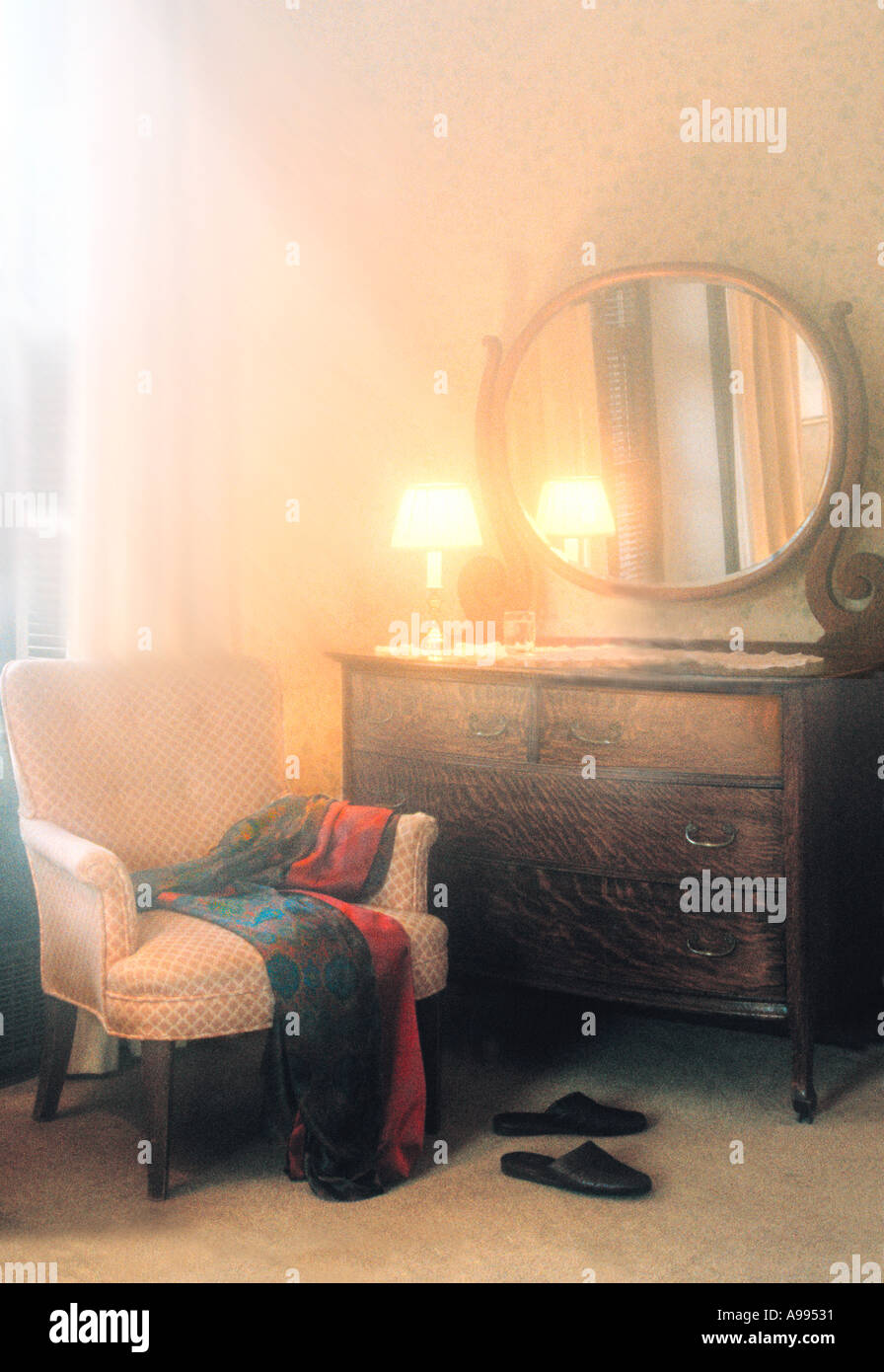 Slippers laying beneath a chair with a robe draped across it Stock