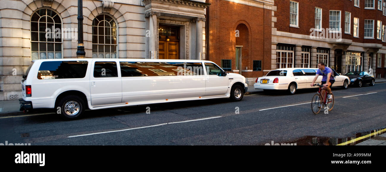 Cyclist passing two stretch limos parked quiet street near US Embassy in London Stock Photo