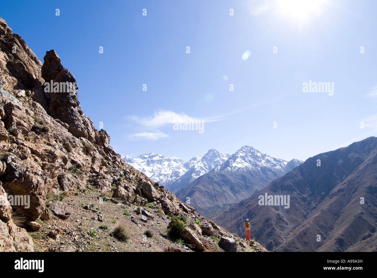 Trekker overlooking the vast Mizane Valley towards the snowy Toubkal mountain range of the High Atlas Mountains of Morocco Stock Photo
