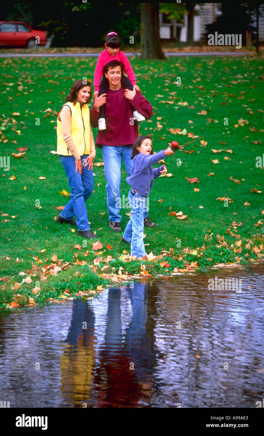 Hispanic couple and their two daughters playing beside a lake Stock Photo